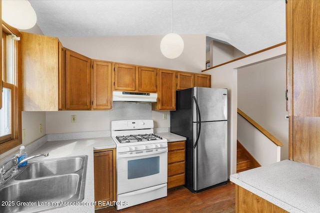 kitchen with white gas range, lofted ceiling, freestanding refrigerator, a sink, and under cabinet range hood