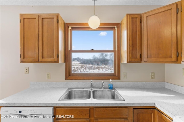 kitchen with brown cabinets, white dishwasher, light countertops, and a sink