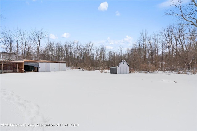 yard covered in snow with a storage shed and an outbuilding