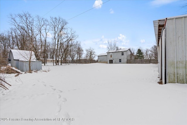 yard covered in snow featuring fence and an outbuilding