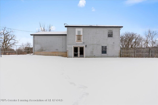 snow covered house featuring fence