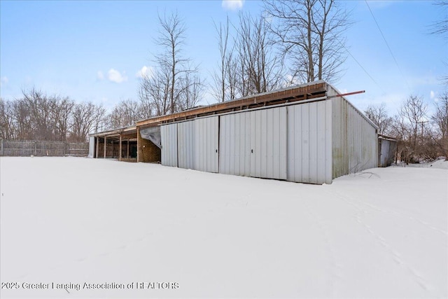 snow covered structure with an outbuilding