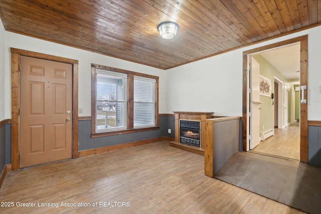 foyer entrance featuring wooden ceiling, a wainscoted wall, wood finished floors, a lit fireplace, and a baseboard heating unit