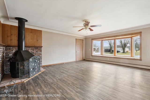 unfurnished living room featuring baseboards, a ceiling fan, a baseboard radiator, wood finished floors, and a wood stove