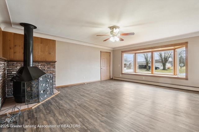 unfurnished living room featuring ceiling fan, wood finished floors, baseboards, baseboard heating, and a wood stove