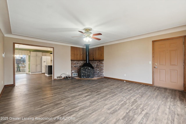 unfurnished living room featuring a ceiling fan, a wood stove, baseboards, and wood finished floors