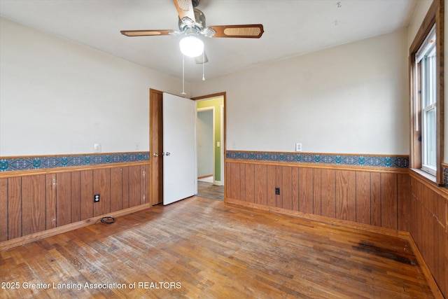 unfurnished room with wooden walls and wainscoting