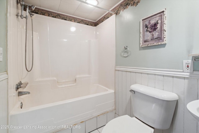 full bathroom with toilet, a wainscoted wall, and shower / washtub combination