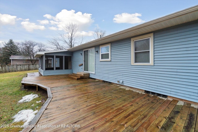 wooden deck featuring a sunroom, fence, and a lawn