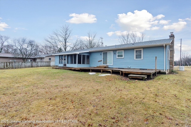 rear view of house featuring a sunroom, a chimney, fence, a deck, and a yard