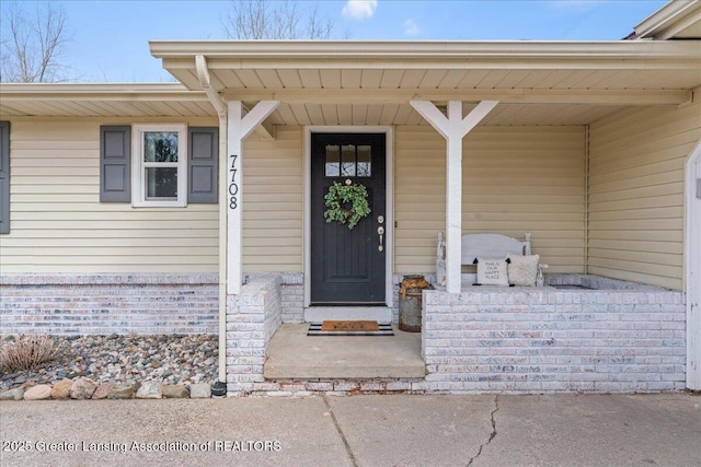 property entrance with a porch and brick siding