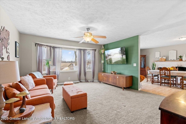 carpeted living area with ceiling fan, a textured ceiling, and baseboards