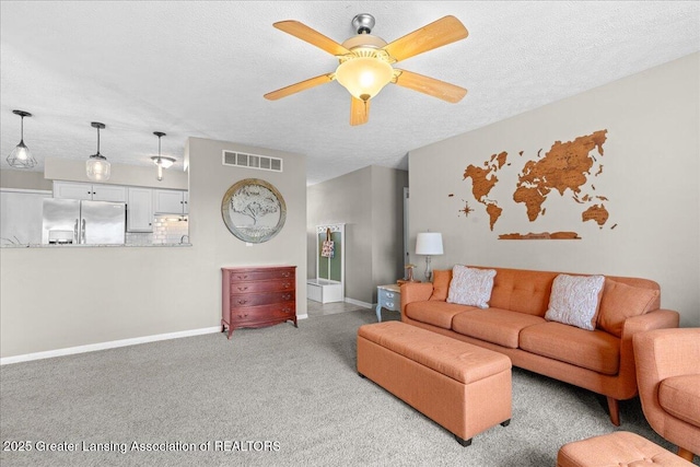 living area featuring baseboards, visible vents, ceiling fan, carpet, and a textured ceiling