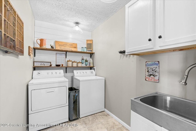 laundry room featuring cabinet space, a sink, a textured ceiling, independent washer and dryer, and baseboards