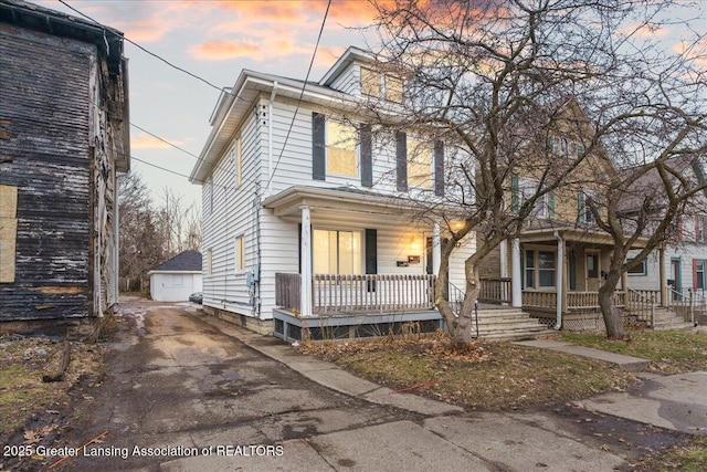 american foursquare style home with a garage, a porch, and an outdoor structure