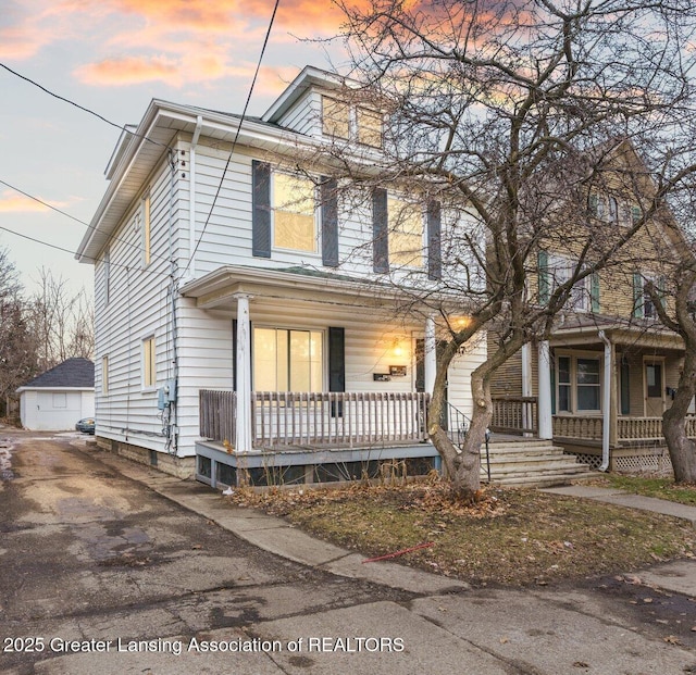 american foursquare style home with a porch and an outbuilding