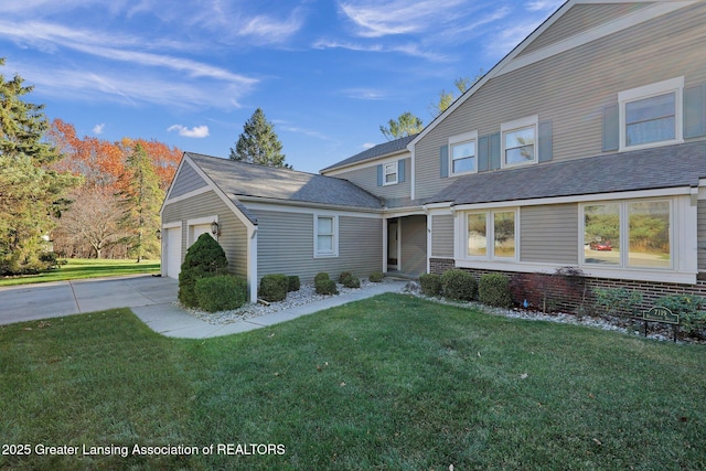 view of front of property featuring an attached garage, driveway, a front lawn, and brick siding