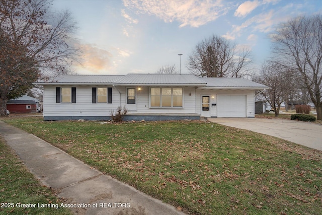 ranch-style house with a garage, metal roof, a lawn, and concrete driveway