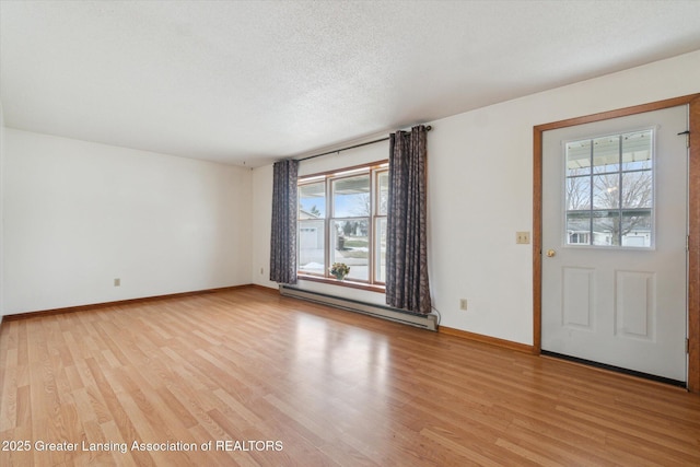 interior space with a baseboard heating unit, light wood finished floors, a textured ceiling, and baseboards