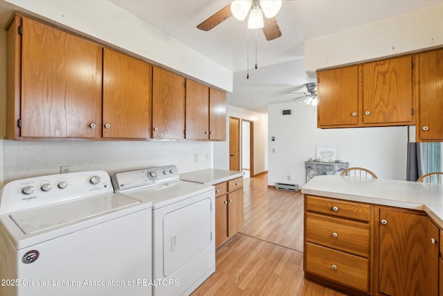 washroom with baseboard heating, ceiling fan, light wood finished floors, and separate washer and dryer