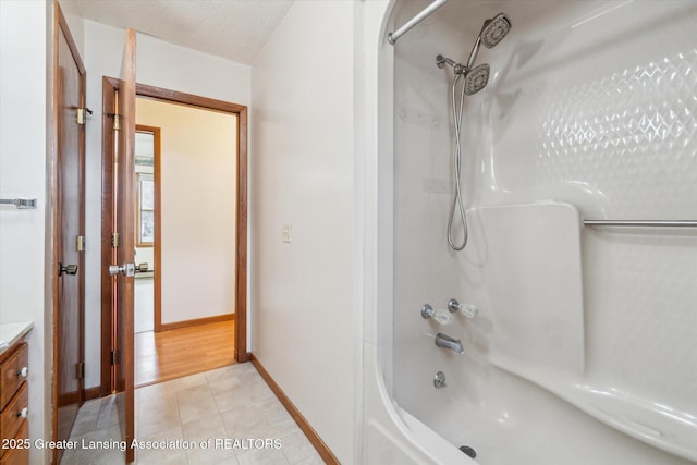 full bathroom featuring tub / shower combination, vanity, a textured ceiling, baseboards, and tile patterned floors