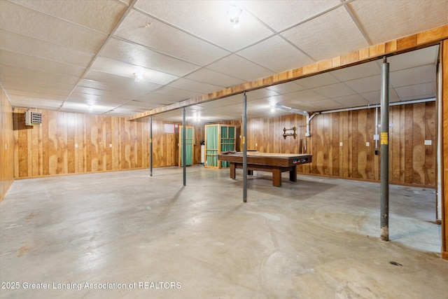 finished below grade area featuring a paneled ceiling, pool table, and wooden walls