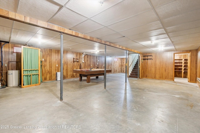 finished basement with wood walls, stairs, and a drop ceiling