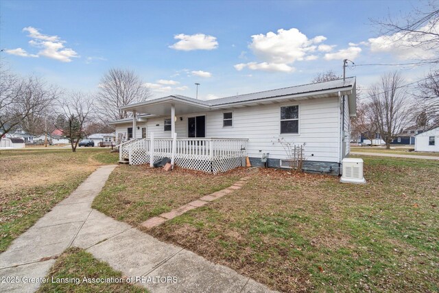 view of front of house with a porch, metal roof, and a front yard