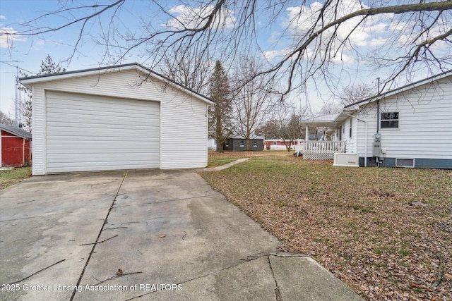 view of side of home with a yard, a detached garage, concrete driveway, and an outdoor structure