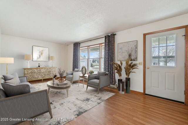 living room with light wood-style flooring, baseboards, and a textured ceiling