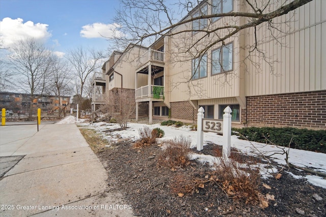 snow covered property featuring brick siding