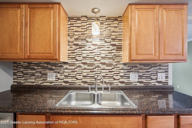 kitchen with dark countertops, a sink, and decorative backsplash