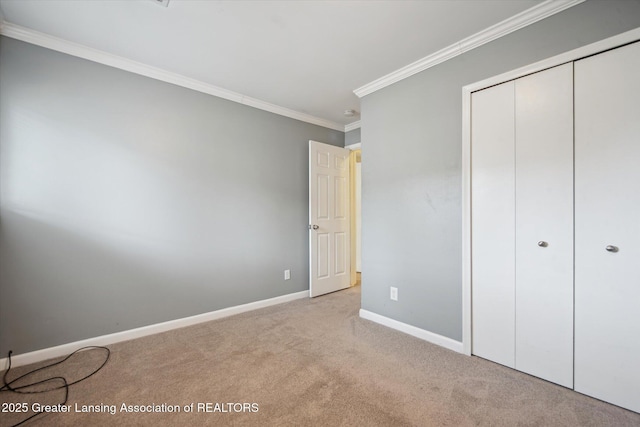 unfurnished bedroom featuring carpet, a closet, baseboards, and crown molding