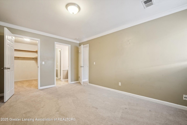 unfurnished bedroom featuring light carpet, visible vents, baseboards, a spacious closet, and ornamental molding