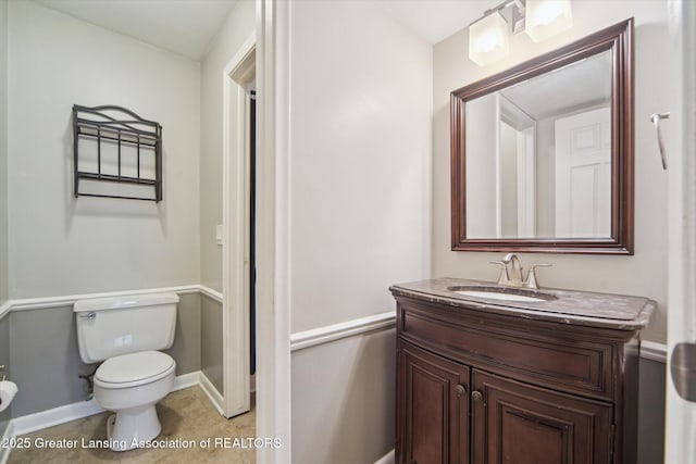 half bathroom with tile patterned floors, vanity, toilet, and baseboards