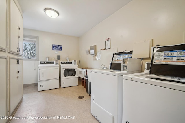 community laundry room featuring baseboards, independent washer and dryer, and light floors