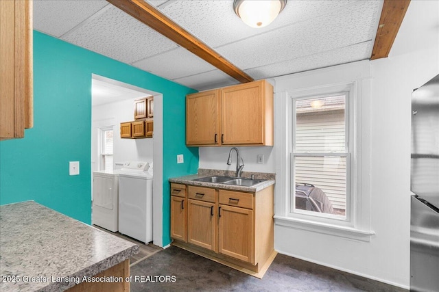 kitchen with concrete flooring, a drop ceiling, a sink, baseboards, and washer and clothes dryer