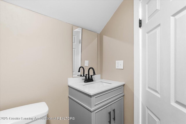 bathroom featuring toilet, vaulted ceiling, and vanity