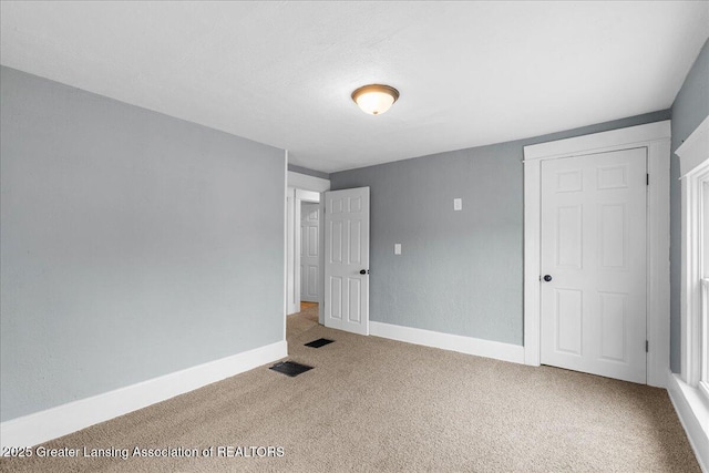 unfurnished bedroom with carpet, visible vents, and baseboards