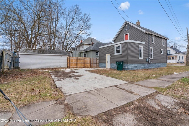 view of property exterior with an outbuilding, a chimney, and fence