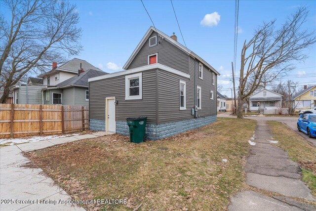 view of side of home featuring fence and a lawn