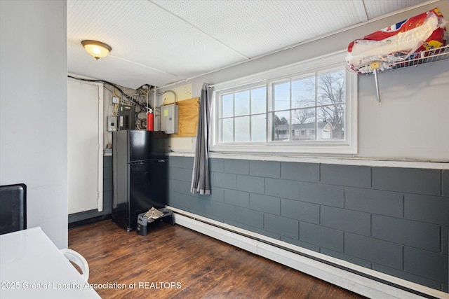 interior space with electric panel, a baseboard heating unit, dark wood-style flooring, and freestanding refrigerator