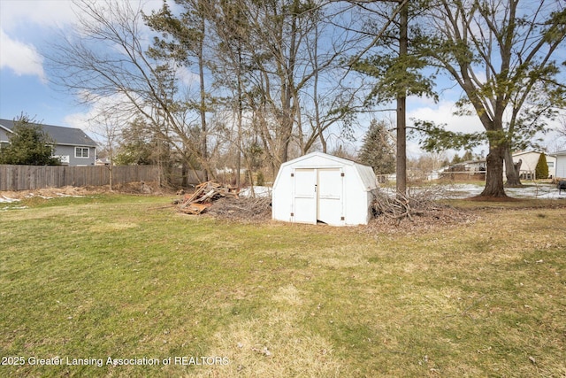 view of yard featuring a storage shed, fence, and an outbuilding