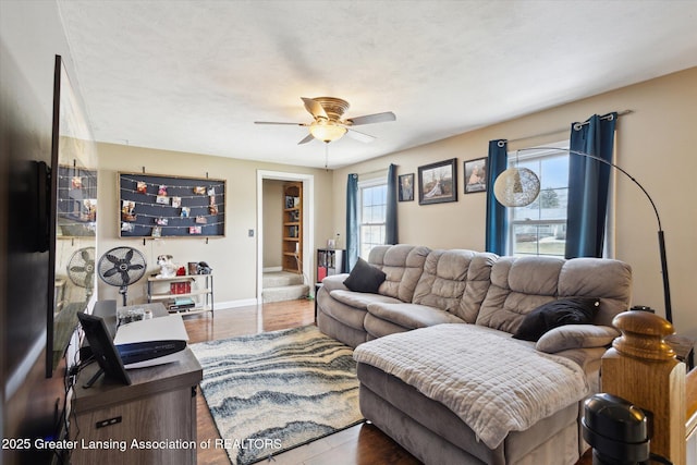 living room featuring wood finished floors, a ceiling fan, and baseboards