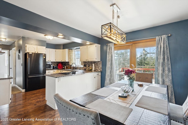 dining space featuring a notable chandelier, baseboards, dark wood finished floors, and a wealth of natural light