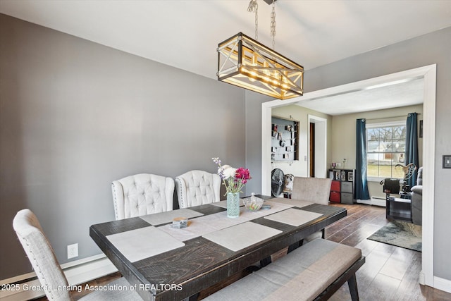 dining area with baseboards, wood finished floors, and a notable chandelier