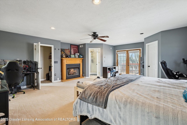 bedroom featuring access to exterior, a lit fireplace, a textured ceiling, french doors, and carpet floors