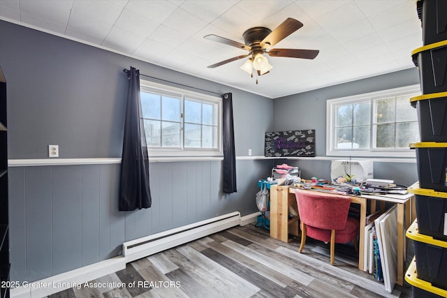 office space with wainscoting, ceiling fan, baseboard heating, and wood finished floors