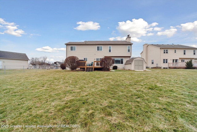 back of property featuring a storage shed, a lawn, an outbuilding, fence, and a deck