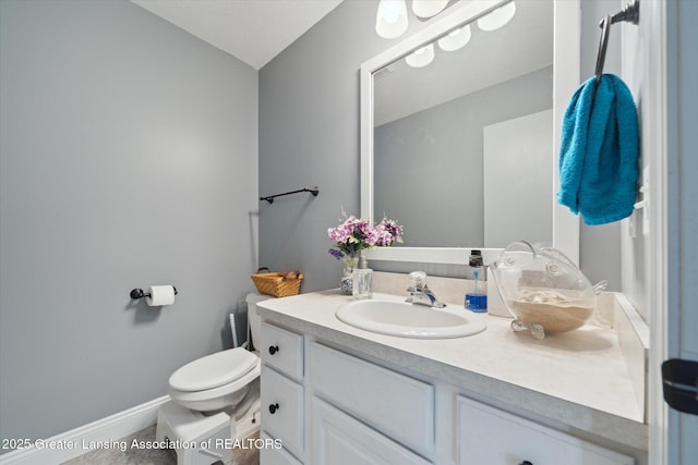 half bath featuring toilet, vanity, and baseboards